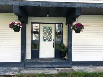 a front door of a house with two potted plants at Bear Valley Guesthouse in Stewart