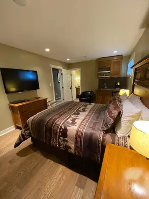a bedroom with a large bed and a flat screen tv at Fitzhugh House Guest Accomodation in Jasper
