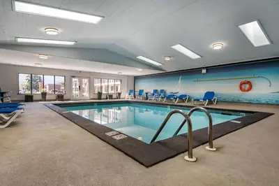a large swimming pool with blue chairs in a room at SureStay Plus Hotel by Best Western Salmon Arm in Salmon Arm