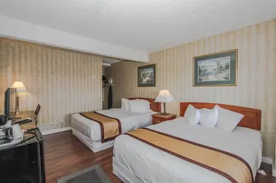 a hotel room with two beds and a television at Canadas Best Value Inn Chinook Station in Calgary