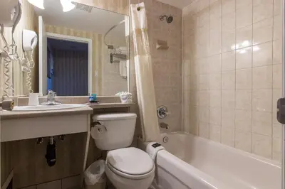 a bathroom with a toilet and a sink and a tub at Canadas Best Value Inn Chinook Station in Calgary