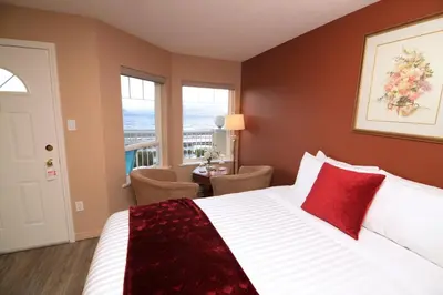 a bedroom with a large bed with red pillows at Casa Grande Inn in Qualicum Beach