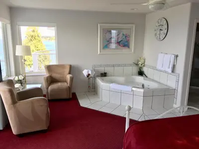 a large bathroom with a large tub and a chair at Casa Grande Inn in Qualicum Beach