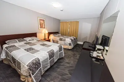 a hotel room with two beds and a desk at Olympia Lodge in Calgary
