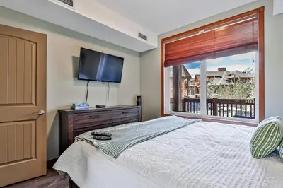 a bedroom with a bed and a tv and a window at Inviting Rocky Mountain HOT TUB in Top Rated Condo managed by Little Sister Getaways in Canmore