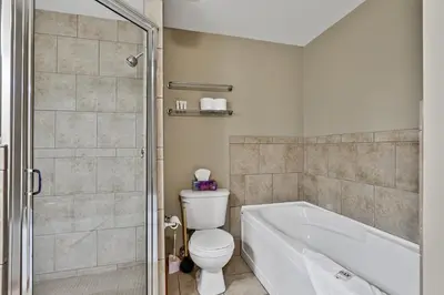 a bathroom with a tub and a toilet and a shower at Inviting Rocky Mountain HOT TUB in Top Rated Condo managed by Little Sister Getaways in Canmore