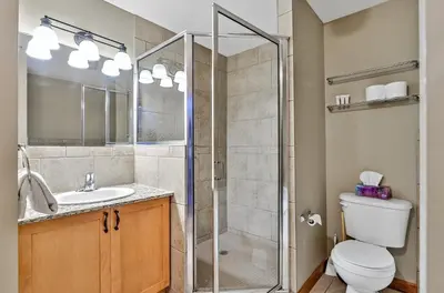 a bathroom with a shower and a toilet and a sink at Inviting Rocky Mountain HOT TUB in Top Rated Condo managed by Little Sister Getaways in Canmore