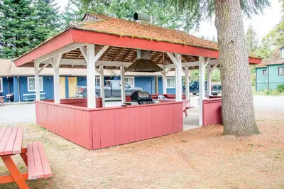 a pavilion with a grill in front of a tree at Riverside Resort & RV Park in Qualicum Beach