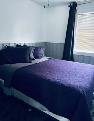 a bedroom with a bed with purple sheets and a window at Sunset Motel in Radium Hot Springs
