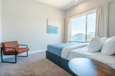 a bedroom with a bed and a chair and a window at West Coast Wilderness Lodge in Egmont