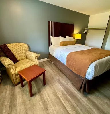 a hotel room with a bed and a chair at Swiss Village Inn in Golden