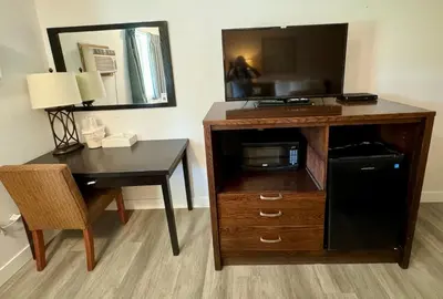 a room with a desk and a tv and a table and a deskictericter at Swiss Village Inn in Golden