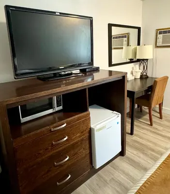 a entertainment center with a flat screen tv and a desk at Swiss Village Inn in Golden
