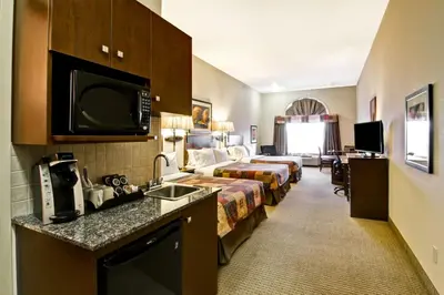 a hotel room with a bed and a kitchen with a sink at Canalta Camrose in Camrose
