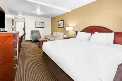 a hotel room with a large bed and a living room at SureStay Plus Hotel by Best Western Drumheller in Drumheller