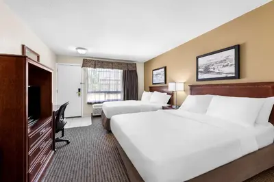 a hotel room with two beds and a flat screen tv at SureStay Plus Hotel by Best Western Drumheller in Drumheller