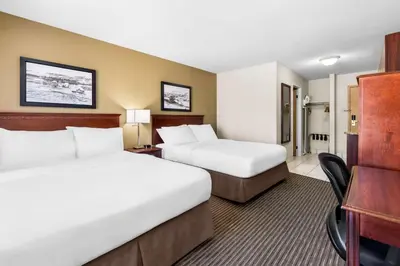a hotel room with two beds and a desk at SureStay Plus Hotel by Best Western Drumheller in Drumheller