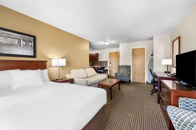 a hotel room with a large bed and a desk at SureStay Plus Hotel by Best Western Drumheller in Drumheller