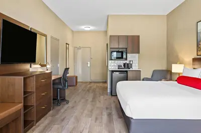 a hotel room with a bed and a desk with a television at Ramada by Wyndham Drumheller Hotel & Suites in Drumheller