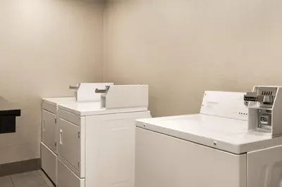 a laundry room with white cabinets and a washer and dryer at Canalta Airdrie in Airdrie
