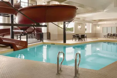 a large pool with a slide in a hotel room at Canalta Airdrie in Airdrie