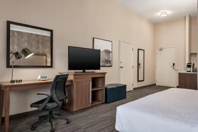 a hotel room with a desk with a television and a bed at Canalta Airdrie in Airdrie
