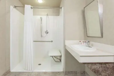 a white bathroom with a shower and a sink at Ramada by Wyndham Camrose in Camrose
