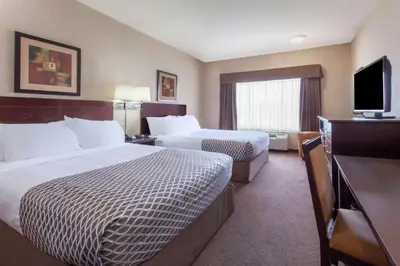 a hotel room with two beds and a flat screen tv at Ramada by Wyndham Camrose in Camrose