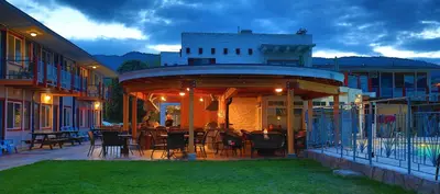 a building with a patio with tables and chairs at Bowmont Motel in Penticton