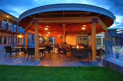 a patio with tables and chairs under a wooden pergola at Bowmont Motel in Penticton