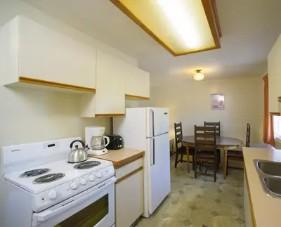 a kitchen with a stove and a white refrigerator at Bowmont Motel in Penticton