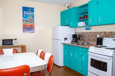 a kitchen with green cabinets and a table with chairs at Bowmont Motel in Penticton