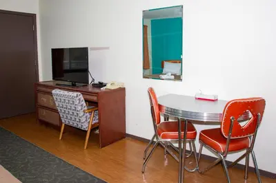 a room with a desk and a table and chairs at Bowmont Motel in Penticton