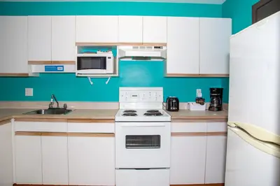 a kitchen with white cabinets and a white stove top oven at Bowmont Motel in Penticton