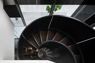 a spiral staircase in a building with a person walking down it at Hotel Le Germain Calgary in Calgary