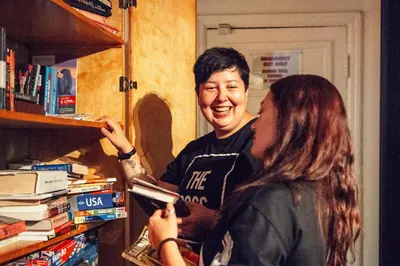 a man and a woman standing next to a book shelf at Ocean Island Inn | Backpackers | Suites in Victoria