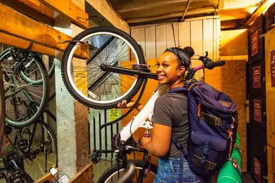 a woman with a backpack holding a bike at Ocean Island Inn | Backpackers | Suites in Victoria