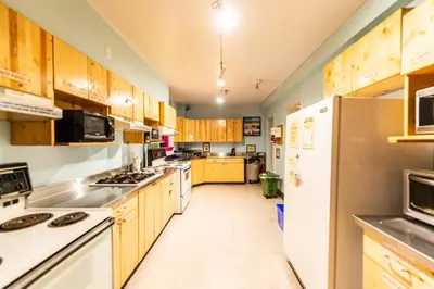 a large kitchen with wooden cabinets and white appliances at Ocean Island Inn | Backpackers | Suites in Victoria