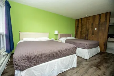 two beds in a room with green walls at Camrose Motel in Camrose