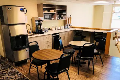 a room with tables and chairs and a kitchen with a counter at Econo Lodge in Okotoks