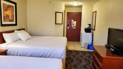 a hotel room with two beds and a flat screen tv at Travelodge by Wyndham Stony Plain in Stony Plain
