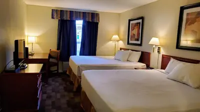 a hotel room with two beds and a desk at Travelodge by Wyndham Stony Plain in Stony Plain