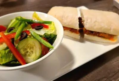 a white plate with a sandwich and a salad at Executive House Suites Hotel & Conference Centre in High Level
