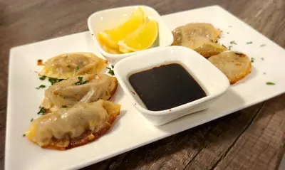 a plate of food with dumplings and a dipping sauce at Executive House Suites Hotel & Conference Centre in High Level