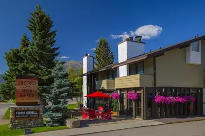 a hotel with red tables and chairs in front of a building at Jasper Inn & Suites by INNhotels in Jasper