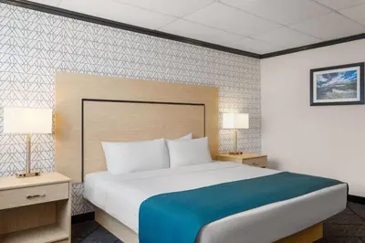a bedroom with a large bed with two night stands and two lamps at Sternwheeler Hotel & Conference Centre, Trademark by Wyndham in Whitehorse
