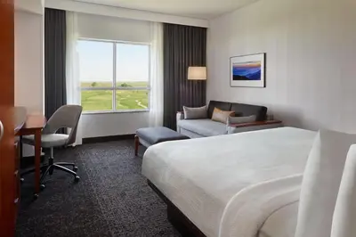 a hotel room with a bed and a couch and a window at Courtyard by Marriott Calgary Airport in Calgary