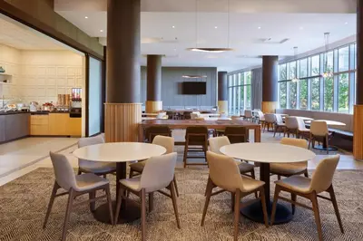 a lobby with tables and chairs and a kitchen at Residence Inn by Marriott Calgary Airport in Calgary
