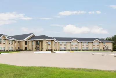 a large building with a large parking lot at High Prairie Inn in High Prairie