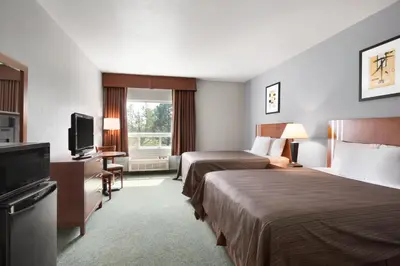 a hotel room with two beds and a flat screen tv at High Prairie Inn in High Prairie